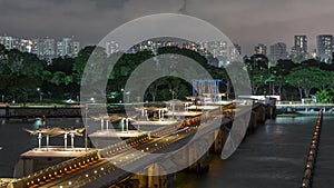 Aerial view Singapore city skyline with bridge at Marina barrage garden night timelapse.