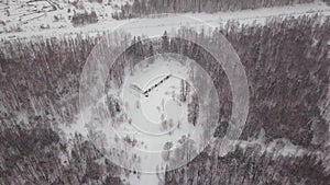 Aerial view of a single-family house in the forest during the winter with lots of snow in the forest and on the roof