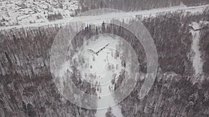 Aerial view of a single-family house in the forest during the winter with lots of snow in the forest and on the roof