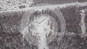 Aerial view of a single-family house in the forest during the winter with lots of snow in the forest and on the roof