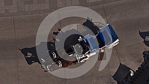 Aerial view of a single fiacre coach with two horses driving on a paved road in the historic center of city Vienna, Austria.