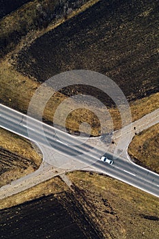 Aerial view of single white car on road through countryside