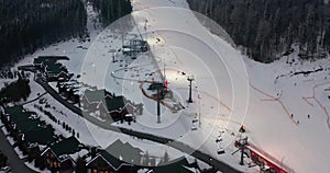 Aerial view: ski resort, slope and chair lift. Cableway lifts skiers to the mountain hill. Winter activity.