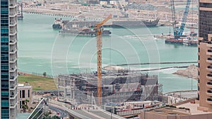 Aerial view of a skyscraper under construction with huge cranes timelapse in Dubai marina.