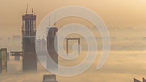 Aerial view of skyscrapers under construction covered by fog in Dubai timelapse.