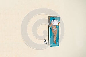 Aerial view of slim woman sunbathing lying on a beach chair in Maldives. Summer seascape with girl. Top view from drone