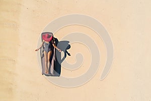 Aerial view of slim woman sunbathing lying on a beach chairin Seychelles. Summer seascape with girl, beautiful waves, colorful