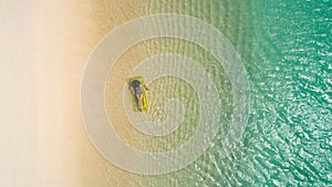 Aerial view of slim woman swimming on the swim mattress in the transparent turquoise sea in Seychelles. Summer seascape with girl