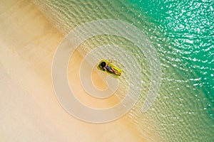 Aerial view of slim woman swimming on the swim mattress in the transparent turquoise sea in Seychelles. Summer seascape with girl