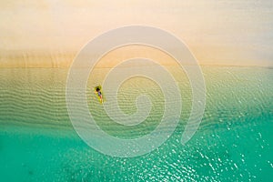 Aerial view of slim woman swimming on the swim mattress in the transparent turquoise sea in Seychelles. Summer seascape with girl