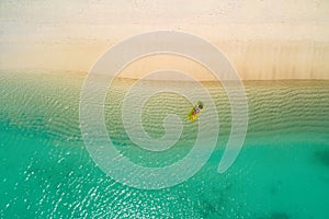 Aerial view of slim woman swimming on the swim mattress in the transparent turquoise sea in Seychelles. Summer seascape with girl