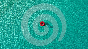 Aerial view of slim woman swimming on the swim ring donut in the transparent turquoise sea in Seychelles. Summer seascape with