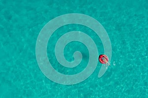 Aerial view of slim woman swimming on the swim ring donut in the transparent turquoise sea in Seychelles. Summer seascape with