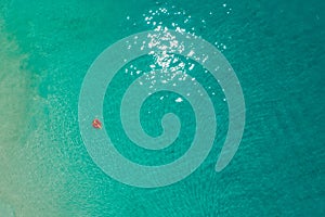 Aerial view of slim woman swimming on the swim ring donut in the transparent turquoise sea in Seychelles. Summer seascape with