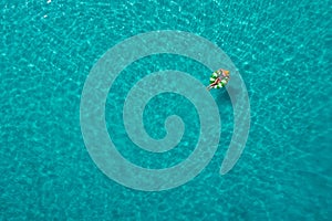 Aerial view of slim woman swimming on the swim ring  donut in the transparent turquoise sea in Seychelles. Summer seascape with