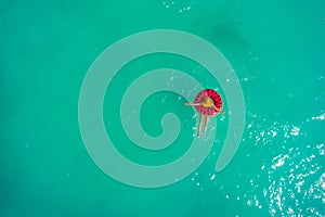 Aerial view of slim woman swimming on the swim ring  donut in the transparent turquoise sea. Summer seascape with girl, beautiful
