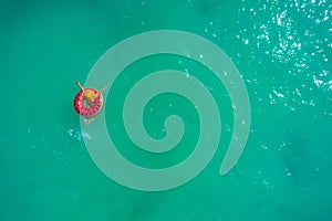 Aerial view of slim woman swimming on the swim ring  donut in the transparent turquoise sea. Summer seascape with girl, beautiful
