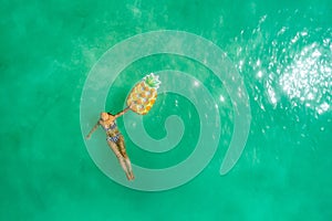 Aerial view of slim woman swimming on the transparent turquoise sea. Summer seascape with girl, beautiful waves, colorful water.