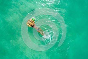 Aerial view of slim woman swimming on the transparent turquoise sea. Summer seascape with girl, beautiful waves, colorful water.
