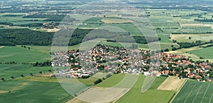 Aerial view from a small airplane from a village near Braunschweig with fields, meadows, farmland and small forests in the area