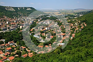 Aerial view of a small, beautiful green city with a lot of trees, situated in a deep karst gorge on a bright summer day. Town of P