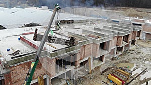 Aerial view of A small construction crane lifts a heavy metal structure. Flying around the construction crane.