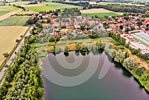 Aerial view of a small German village behind an artificial lake, which was created by sand mining for a concrete plant