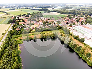 Aerial view of a small German village behind an artificial lake, which was created by sand mining for a concrete plant