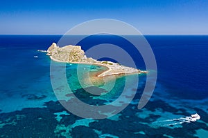 Aerial view of a small island and boats in a crystal clear blue ocean