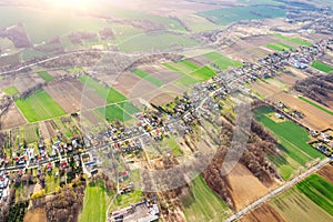Aerial view of a small town among green fields, a small village, a long street and many private houses, landscape