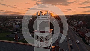 Aerial View of a Small Town and a Steeple as the Sun Behind the Camera Breaks the Horizon