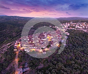 Aerial view of a small village surrounded by green landscapes at susnet