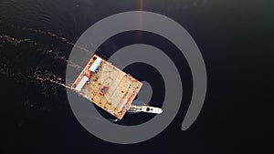 Aerial view of small wooden ferry crossing the river with orange car on it. Traditional ferry boat on water