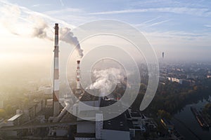 Aerial view of smoking chimneys of CHP plant and smog over the city and builidings in the background