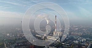 Aerial view of smoking chimneys of CHP plant and smog over the city and builidings in the background - Wroclaw, Poland