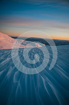 Aerial view of snow-capped mountain during sunset, captured with a handheld camera