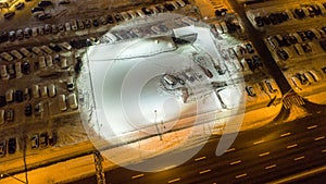 Aerial view of snow-covered cars stand in the parking lot on a winter nigth