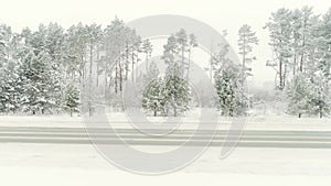 Aerial view of a snow covered empty road and winter forest. Scene. Natural background with mixed forest growing along