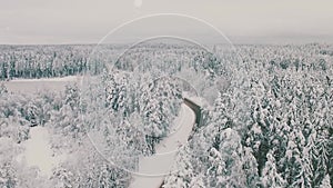 Aerial view of a snow covered empty road and winter forest. Scene. Natural background with mixed forest growing along