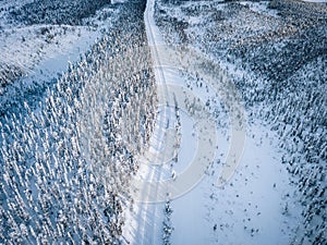 Aerial view of snow covered winter forest and road. Beautiful rural landscape in Finland