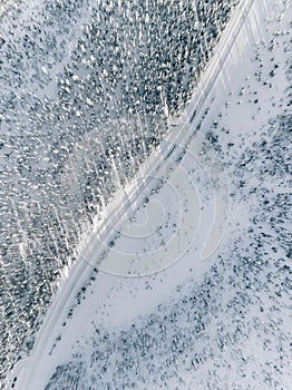 Aerial view of snow covered winter forest and road. Beautiful rural landscape in Finland