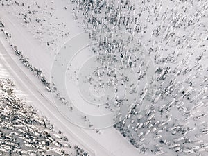 Aerial view of snow covered winter forest and road. Beautiful rural landscape in Finland