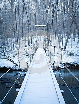Aerial view of snow covered wooden bridge over Eno river surrounded by frozen trees