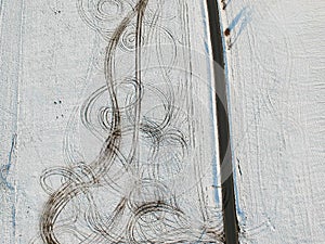 Aerial view of snow fields splitted by tar road with lines of offroad car in field