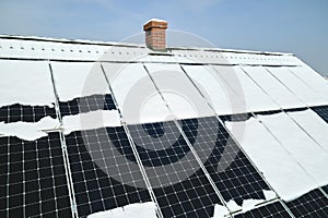 Aerial view of snow melting from covered solar photovoltaic panels installed on house rooftop for producing clean