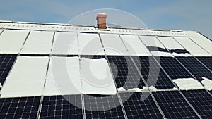 Aerial view of snow melting from covered solar photovoltaic panels installed on house rooftop for producing clean