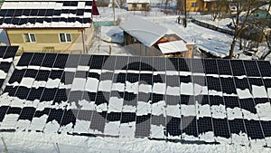 Aerial view of snow melting from covered solar photovoltaic panels installed on house rooftop for producing clean