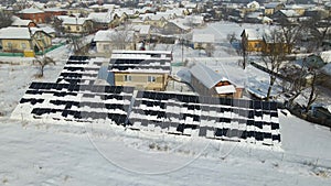 Aerial view of snow melting from covered solar photovoltaic panels installed on house rooftop for producing clean