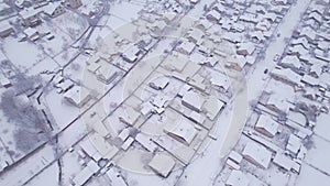 Aerial view of the snow village with private houses and garden plots at winter