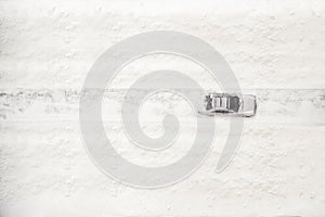 Aerial view on snowy car moving on the road at the winter time. Seasonal Snowfall